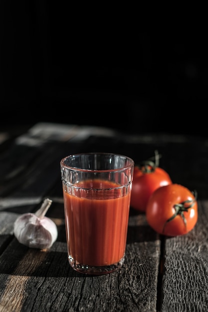 Vaso de jugo de tomate fresco, tomate y ajo.