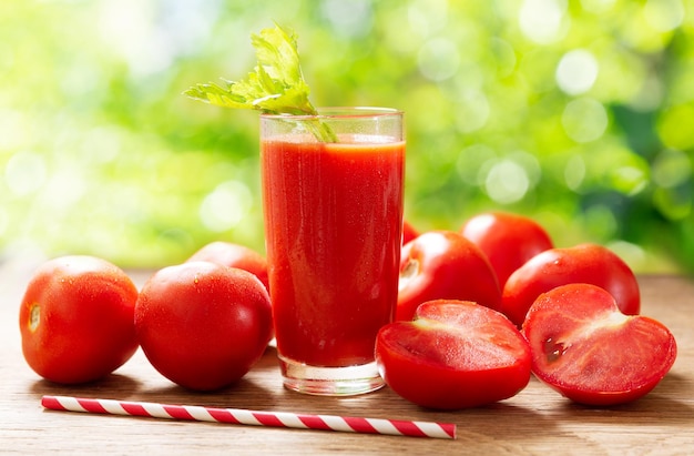 Vaso de jugo de tomate con tomates frescos en la mesa de madera