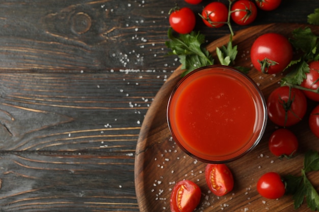 Foto vaso de jugo de tomate, tomates y sal en madera