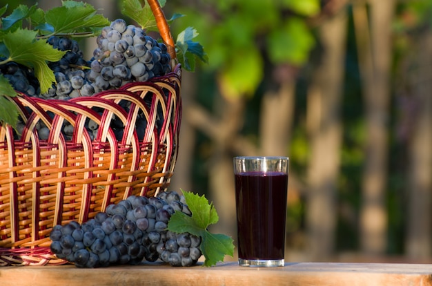 Vaso de jugo de uva con cesta de mimbre de uva