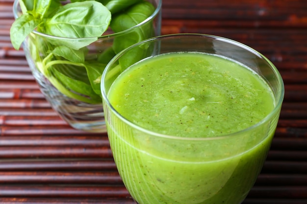 Un vaso de jugo verde saludable con espinaca y albahaca en la mesa de cerca