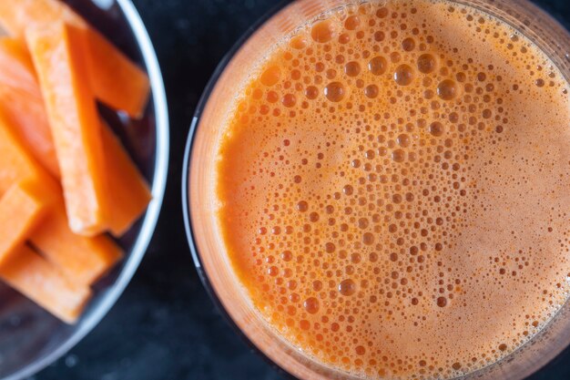 Vaso de jugo de zanahoria fresca de fondo, vista superior, de cerca. Concepto de comida sana