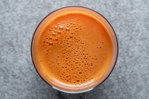 Vaso de jugo de zanahoria fresca de fondo, vista superior, de cerca. Concepto de comida sana