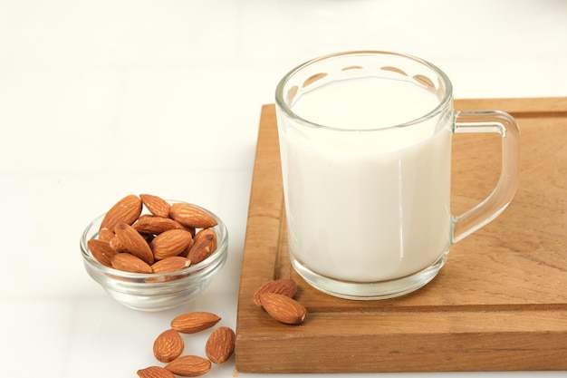 un vaso de leche de almendra con almendra en un fondo claro