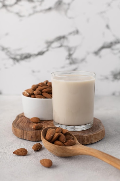 Vaso de leche de almendras con nueces sobre una tabla de madera sobre un fondo claro