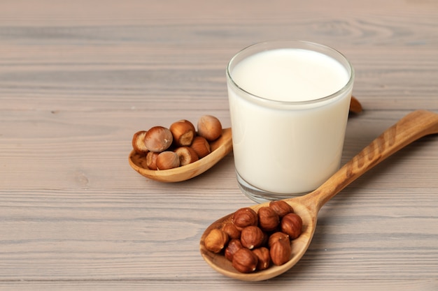 Vaso de leche y avellanas en mesa de madera