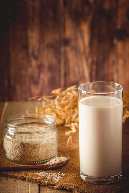 Vaso de leche de avena sobre un fondo de madera Leche de dieta vegetal sin lactosa Bebida de avena sin gluten