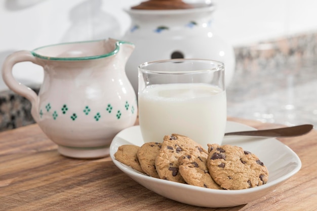 Vaso de leche y bandeja con galletas con chispas de chocolate