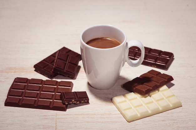 Vaso de leche con chocolate y variedad de chocolates en la mesa