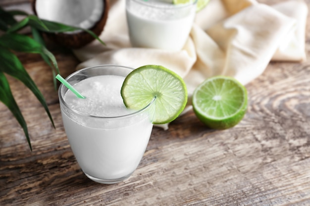 Vaso de leche de coco fresca con limón sobre mesa de madera