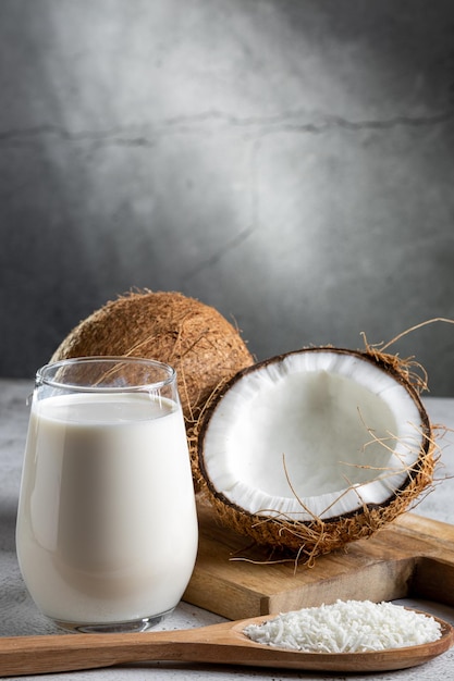 Vaso de leche de coco con trozos de coco sobre la mesa