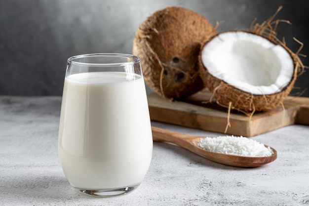 Vaso de leche de coco con trozos de coco sobre la mesa