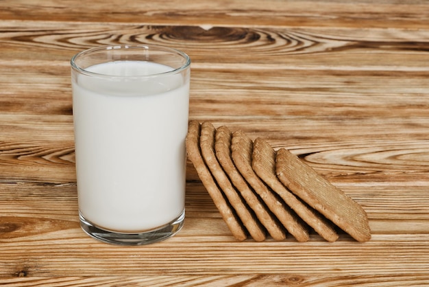 Vaso de leche fresca y galletas dulces en la mesa de madera