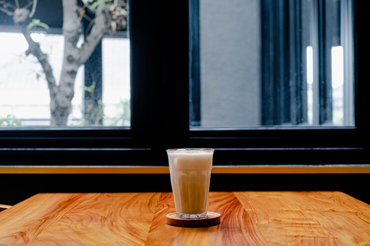 Un vaso de leche fresca helada en medio de una mesa de madera
