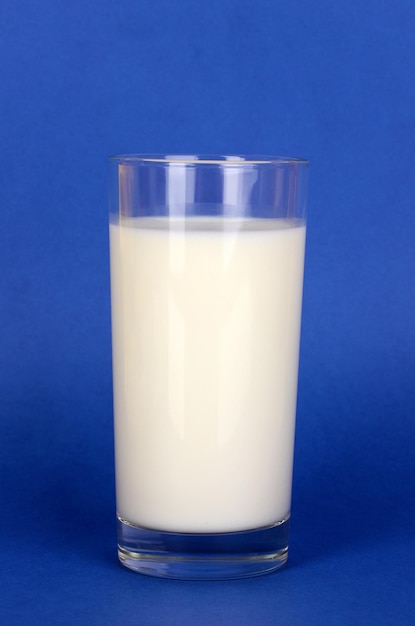 Foto vaso de leche fresca sobre fondo azul.