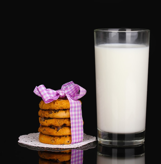 Vaso de leche y galletas aislado en negro