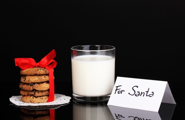 Vaso de leche y galletas aislado en negro