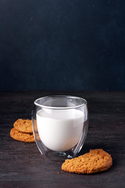 Un vaso de leche y galletas de avena sobre un fondo oscuro una copia del enfoque selectivo del espacio