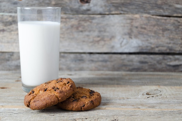 Vaso de leche y galletas con chispas de chocolate sobre fondo de maderaVillage Breakfast