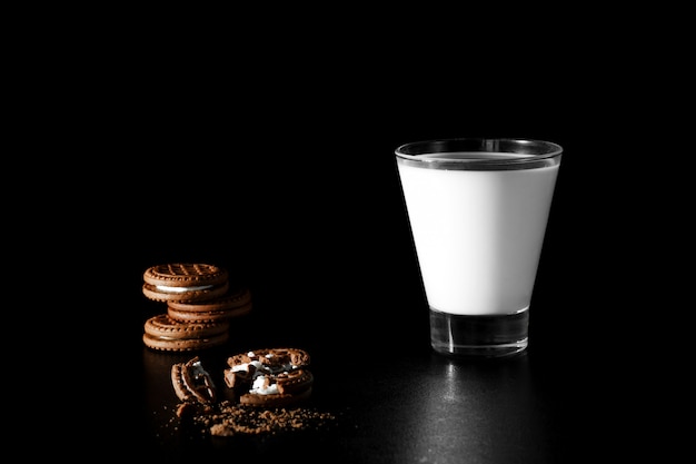 Vaso de leche y galletas de chocolate en negro