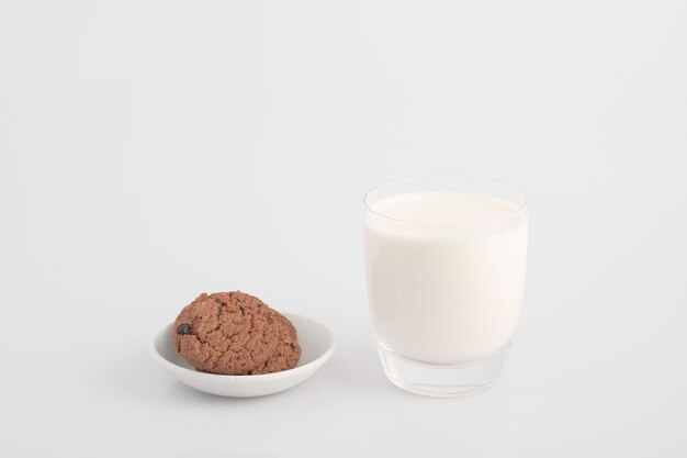 Vaso de leche y galletas de chocolate sobre un fondo blanco,