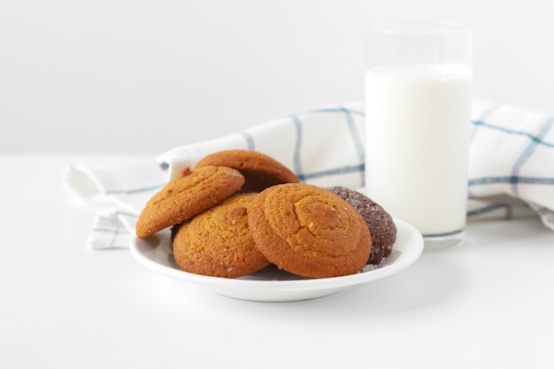 Vaso de leche y galletas con paño de cocina en luz