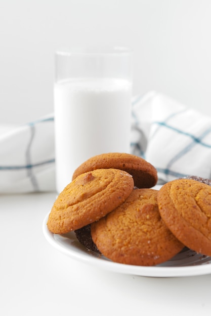 Vaso de leche y galletas con paño de cocina en la pared de luz