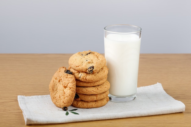 Vaso de leche y galletas con pasas sobre la mesa