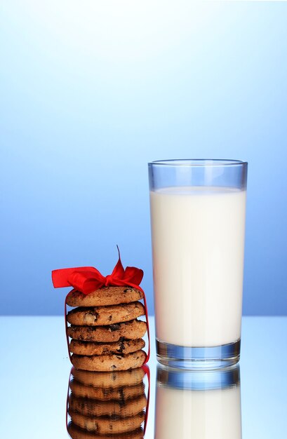 Vaso de leche y galletas sobre fondo azul.