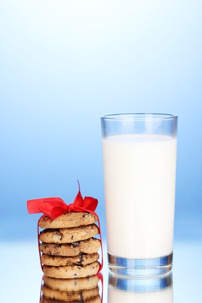 Vaso de leche y galletas sobre fondo azul.