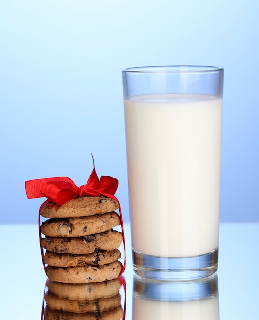 Vaso de leche y galletas sobre fondo azul.