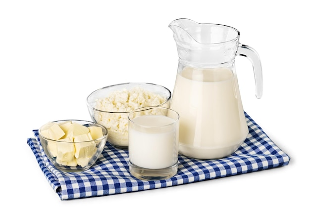 Un vaso de leche y una jarra de leche en un mantel de cuadros