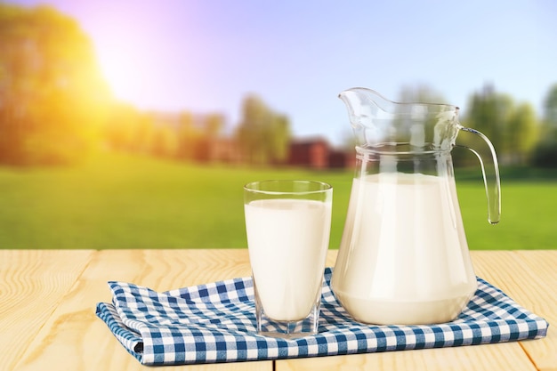 Vaso de leche y jarra sobre fondo borroso