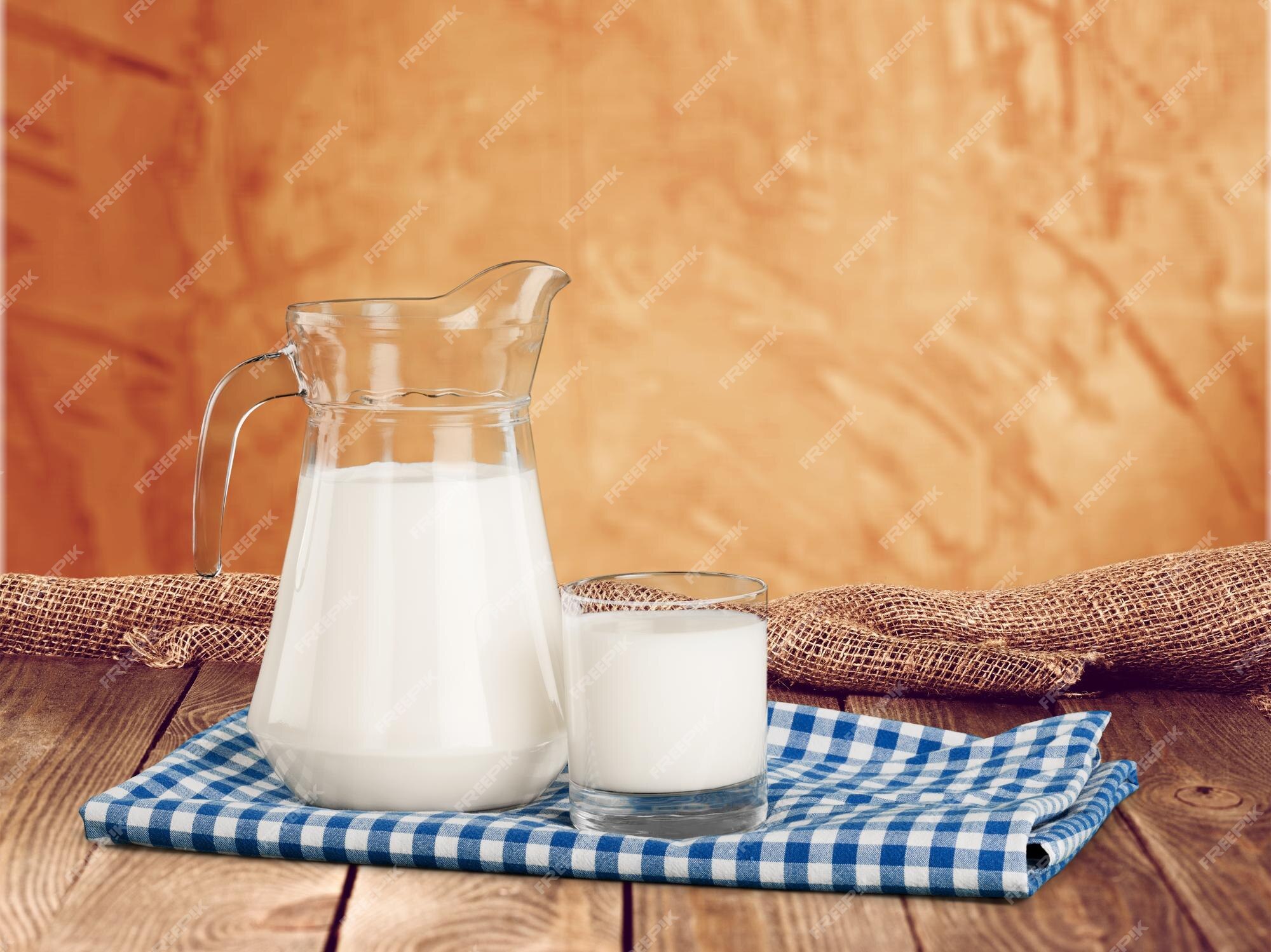 Jarra de leche y vaso sobre mesa de madera