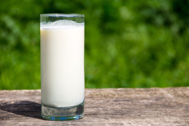 Vaso de leche en la mesa de madera con fondo de naturaleza