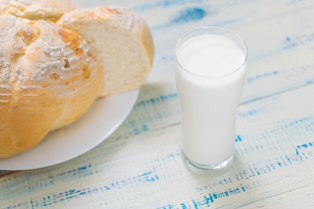 Un vaso de leche y pan blanco sobre un fondo de madera