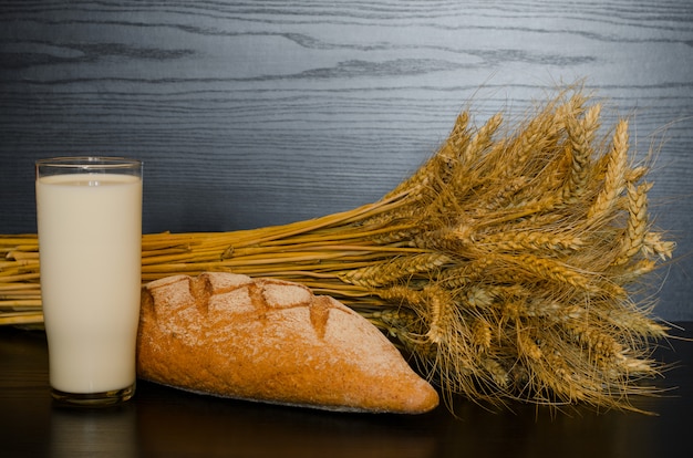 Un vaso de leche, pan integral y una gavilla.