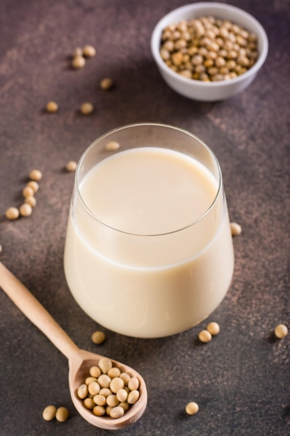 Vaso de leche de soja y frijoles de soja sobre la mesa Proteína vegetal Vista vertical