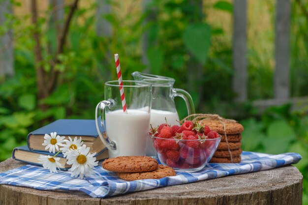 Vaso de leche y tazón de bayas frescas en un ambiente al aire libre