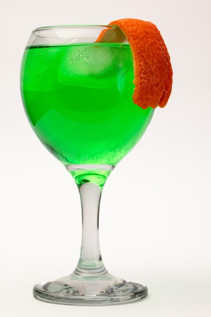 Foto vaso de licor verde con hielo y cáscara de naranja