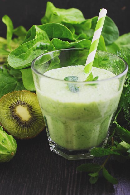 Un vaso de licuado con verduras verdes y espinacas.