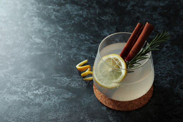 Vaso de limonada con canela y romero sobre mesa ahumada negra