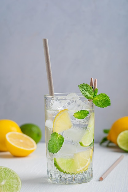 Vaso de limonada dulce refrescante con hojas de menta, rodajas de lima y limón, hielo y tónico en la mesa