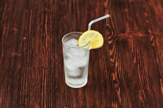 Vaso de limonada fresca con hielo, cóctel en superficie de madera