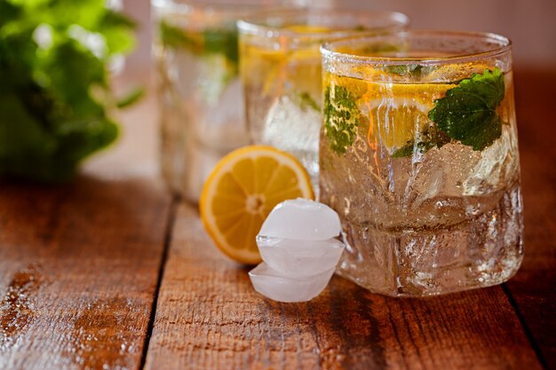 Vaso de limonada con limón fresco y menta sobre fondo de madera