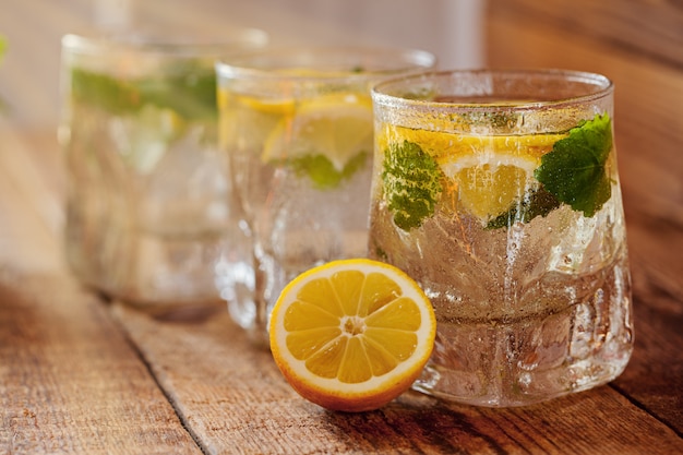 Vaso de limonada con limón fresco y menta sobre fondo de madera