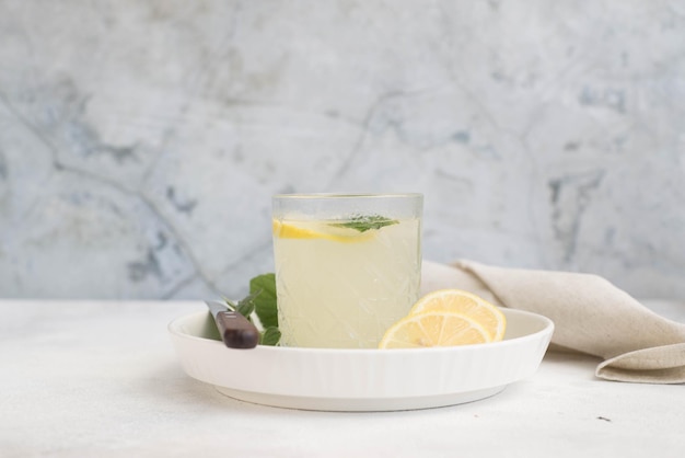 Un vaso de limonada con limón sobre un fondo gris.