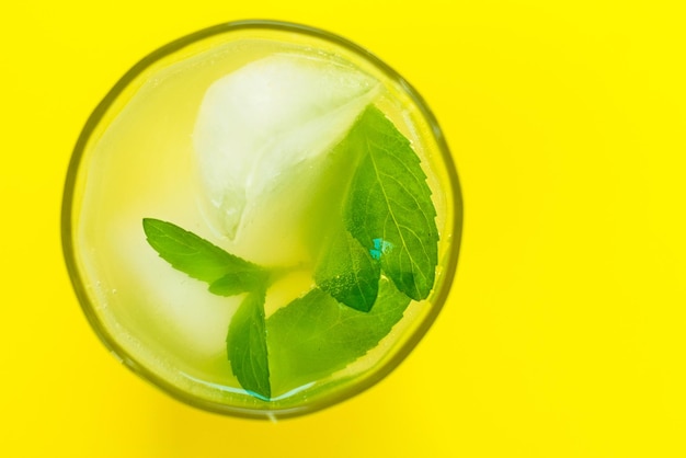 Un vaso de limonada con menta sobre un fondo amarillo brillanteBebida refrescanteVista desde arriba