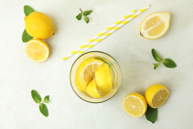 Vaso de limonada, pajitas y limones en la mesa con textura blanca