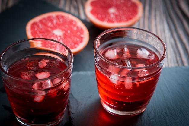 Vaso de limonada de pomelo con cubitos de hielo y gotitas.